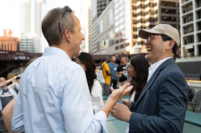 Two attendees laughing mid-conversation with the skyline behind them