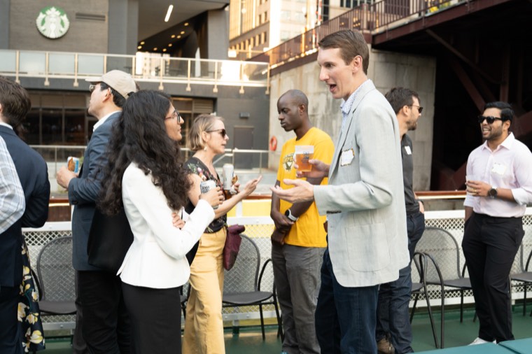 Guests mingling in small groups on the deck as the boat passes under a bridge